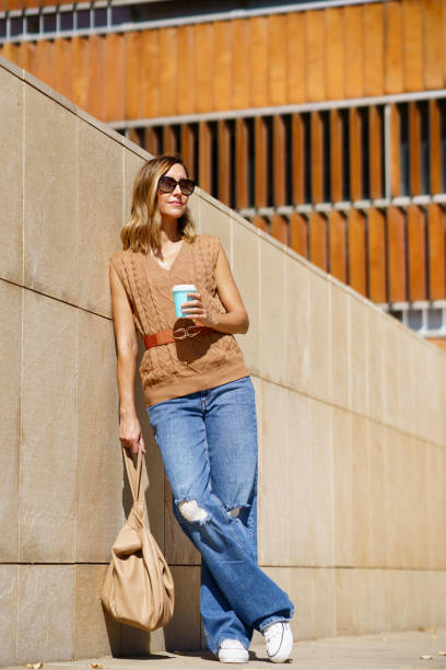 istock Stylish woman with coffee leaning on wall 1462964172