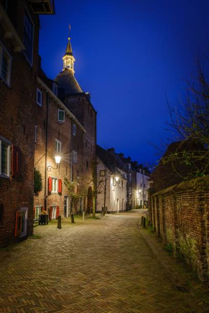 istock Narrow cobblestone alley between brick buildings in a town under blue evening sky 1462964252