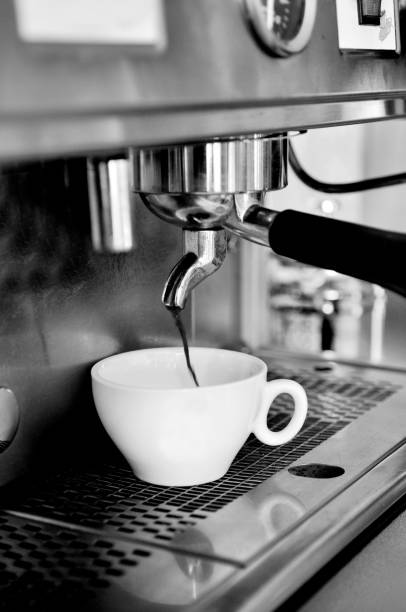 istock Vertical grayscale of coffee pouring from the coffee machine into a cup 1462966143