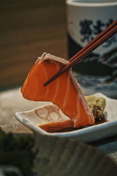 istock Vertical closeup of chopsticks holding salmon sashimi. 1462966282