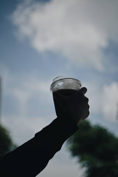istock Vertical closeup of a hand holding a plastic cup with a cold coffee. 1462966495