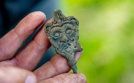 A Viking Age needle and face mask, intact, bronze