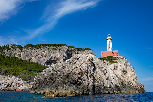 A low angle shot of a lighthouse on a cliff on the shore of Capri, Italy