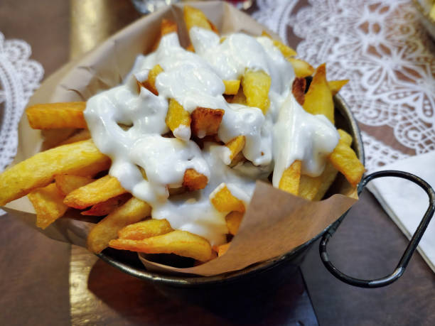 istock French fried potatoes close up served on a small basket cooking tool, with melted white sauce on top. 1462976889