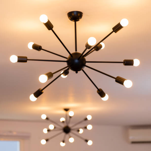 istock Modern minimalistic chandeliers giving orange light suspended from a white ceiling 1462978493