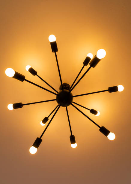 istock Modern minimalistic chandelier giving orange light suspended from a white ceiling 1462978497