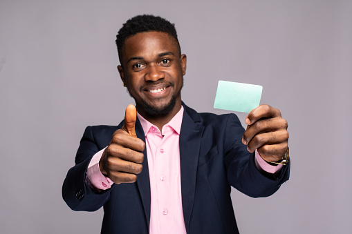 A black man smiling showinga tumbs up and a plain card