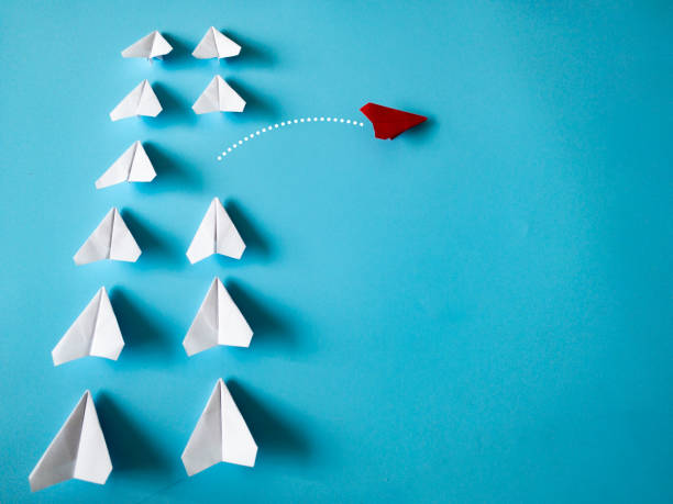 istock Red paper plane origami leaving other white planes on blue background with customizable space for text. Leadership skills concept 1462979678
