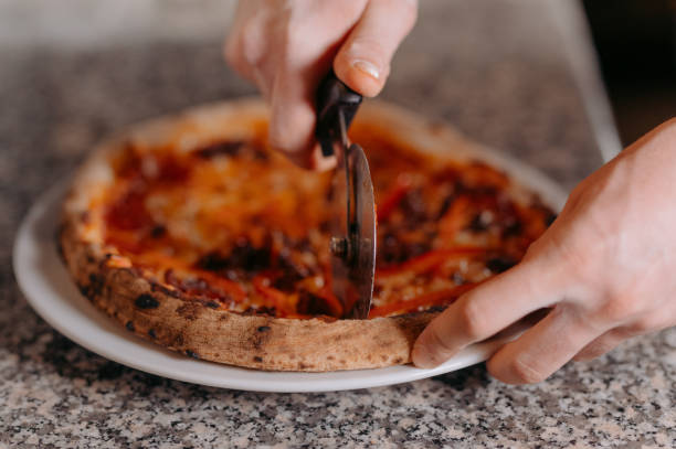 istock Closeup hand of chef baker in white uniform cutting pizza at kitchen 1462980442