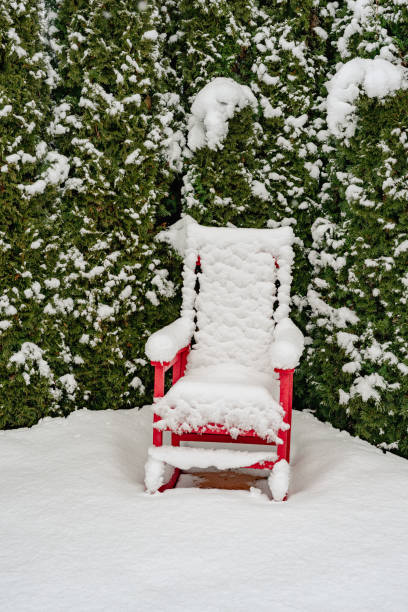 A single lawn chair covered in snow on a deck