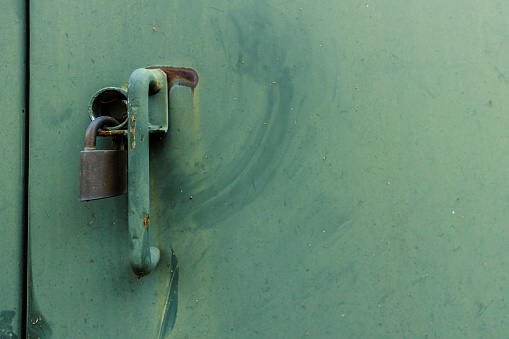 An old green metal door closed with a lock