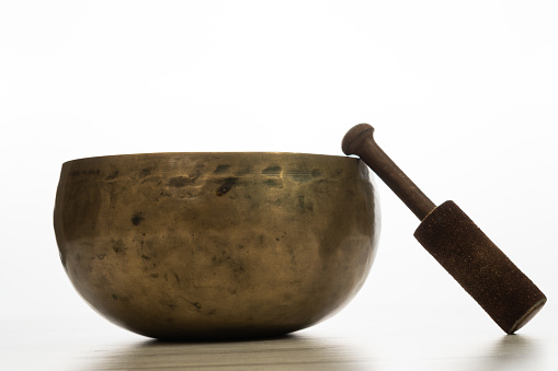 This is a photograph taken in the studio of a Buddhist singing golden bowl isolated on a white background