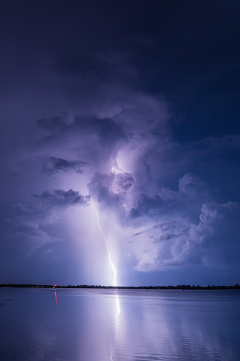 A vertical shot of a stormy sky with striking lightning over water in Florida