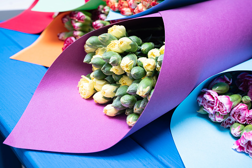 Close up photo of flower bouquets in multicolored papers. Shot under daylight.