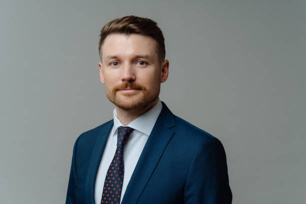istock Handsome unshaven man in suit posing against grey background 1462987249