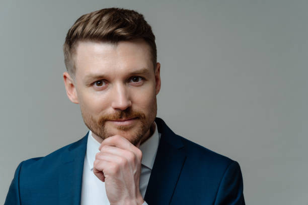 istock Handsome thoughtful entrepreneur thinking about business and looking at camera while standing against grey background 1462987321