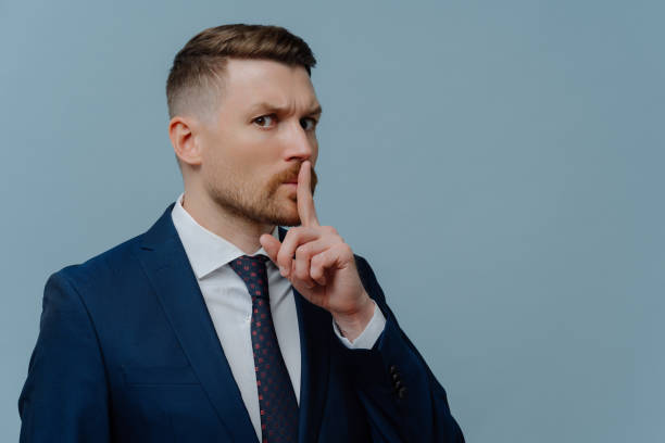 istock Businessman looking at camera and showing shh sign 1462987429