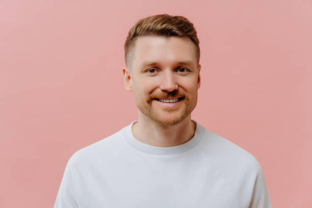 istock Young positive man smiling at camera in pink studio background 1462987471