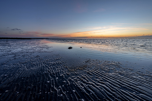 A view of mudflats near the coast of North Sea during sunset in Cuxhaven