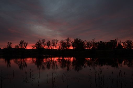 A beautiful shot of a bright sunset sky over a lake and a forest