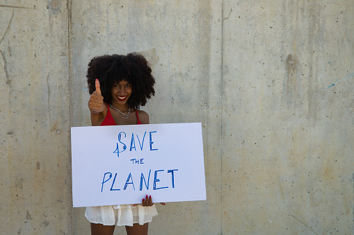 A closeup of a beautiful African-American woman with a banner claiming to save the planet