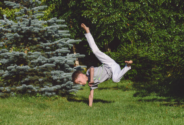 Boy stands on one hand making capoeira kick
