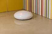 Smart home concept. After accident with plumbing pipe water leaking on floor and wireless flood sensor alarm went off.