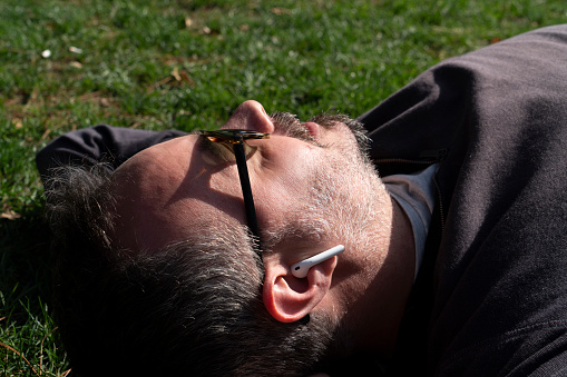 Man with headphones napping on grass