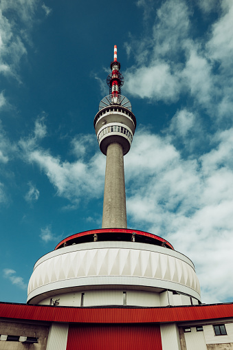 A low angle shot of a TV tower with cloudy sky in the background