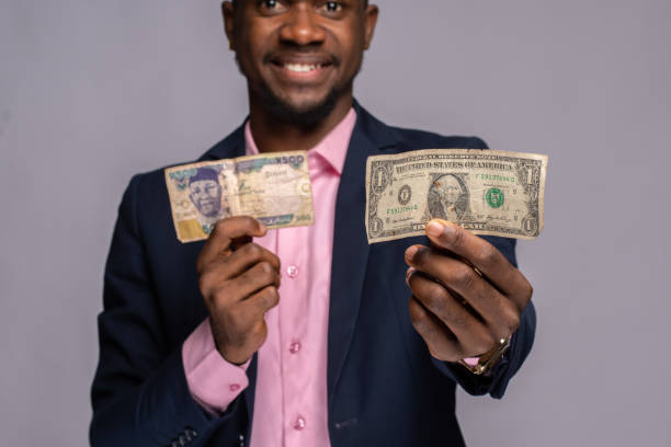 istock Young African businessmaan holding banknotes on a light pink background 1463006294
