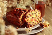 Fruit cake and tea on a wooden table with dried flowers.
