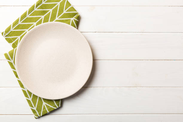 istock Top view on colored background empty round white plate on tablecloth for food. Empty dish on napkin with space for your design 1463028504