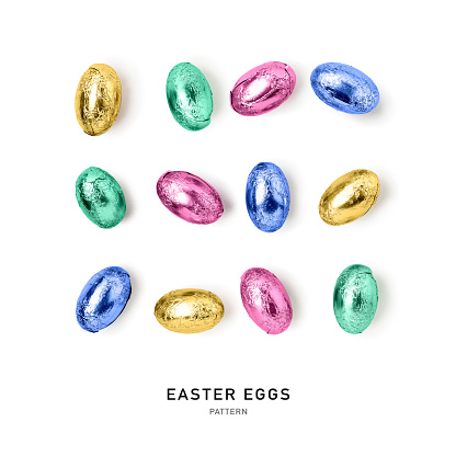 Chocolate easter eggs wrapped in foil. Colorful rainbow candy isolated on white background. Holiday and springtime concept. Creative layout and pattern. Flat lay, top view. Design element