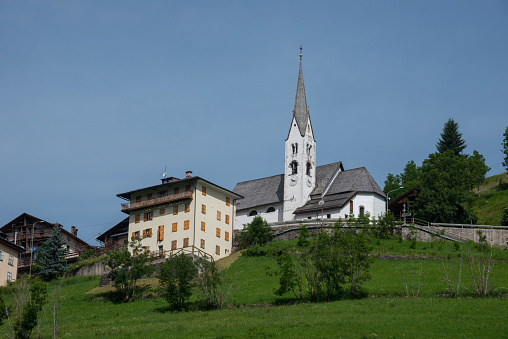 Veneto, Italy - June 28, 2022: Houses and church of San Sebastiano in the village of Falcade Alto