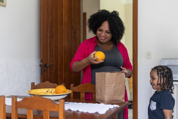 istock Pregnant woman cutting oranges with son 1463045604
