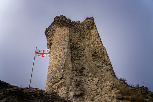 Ruined tower of Ujarma fortress with Georgian flag. Kakheti region, Georgia