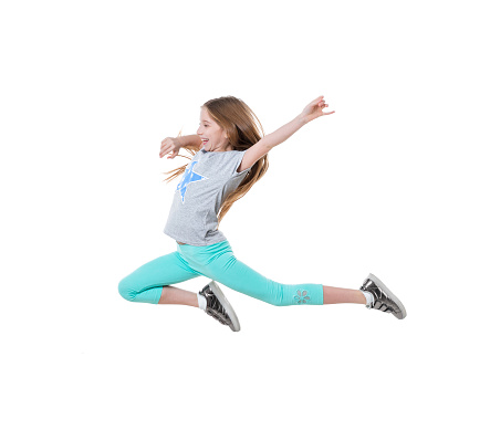 Lovely long-haired girl dancing and feeling good, wearing gray shirt and greenish pants, isolated
