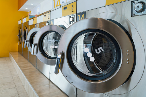 A row of qualified coin-operated washing machines in a public store. Concept of a self service commercial laundry and drying machine in a public room.
