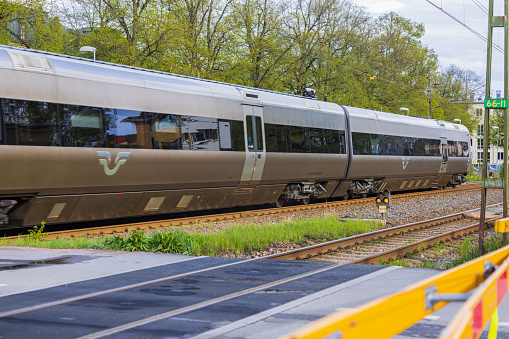 Sweden. Uppsala. 05.14.2022. Close-up view of speed train passing by crossroad. Transportation and safety concept.