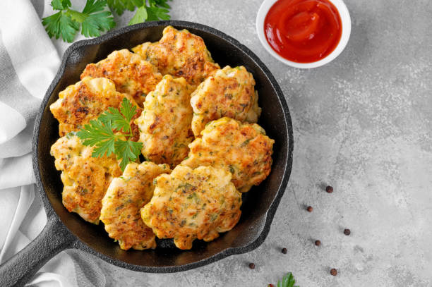 cotolette di pollo a base di carne macinata, cipolla, aglio ed erbe fresche in una padella su uno sfondo di cemento grigio. vista dall'alto, messa a fuoco selettiva. - cutlet foto e immagini stock