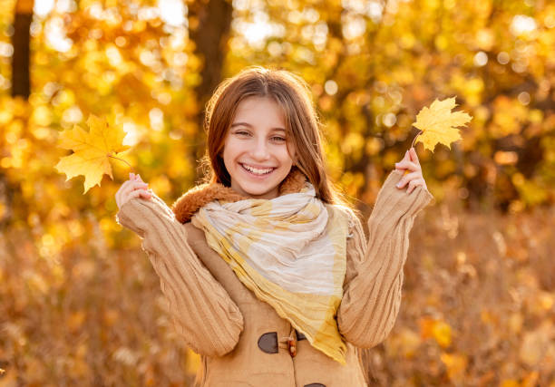 Funny girl with autumn leaf covering her face and tongue out