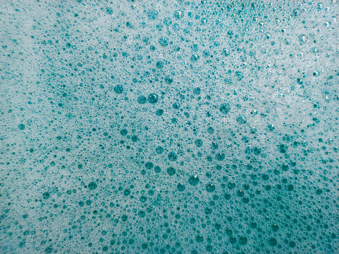Bubbles of oxygen surging upward in blue water. Concept ecology, environment, clean sea, potable water, advertising of cosmetics, washing-up liquids, soaps or an abstract background