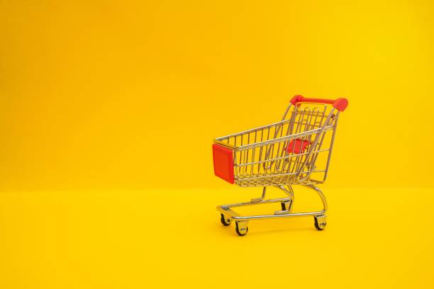 istock Small steel shopping trolley on yellow surface 1463064386