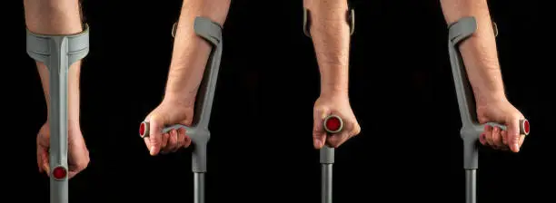 Person hands with forearm crutches. Black isolated background. View of silhouettes from different sides