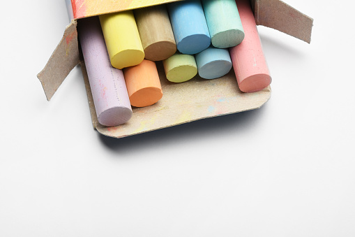 High angle view open box of colorful chalks on the white background with copy space