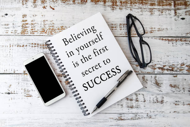 Believing in yourself is the first secret to success. Text on notepad with wooden background. Inspiring Creative Motivation Quote.