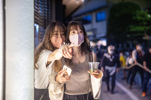 Young female friends looking at performance of Japanese festival