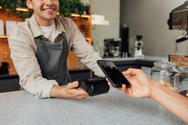 istock Unrecognizable cafe owner holding card machine at the counter while customer making payment by smartphone 1463070763