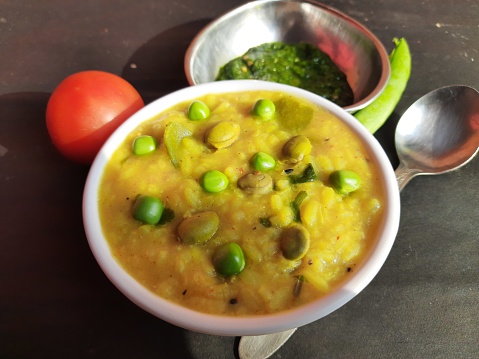 Famous Indian Food Khichdi is ready to serve. Dal khichdi served in bowl. It is made of toovar dal, vegetables and rice combined. Rce Khichdi with tomato, green peas and chilli, served in a bowl.