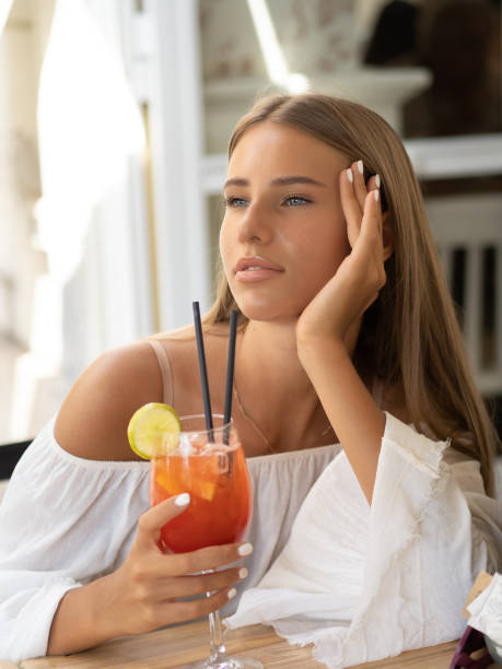 istock A young elegant woman holds a cocktail while sitting outside in summer 1463080032